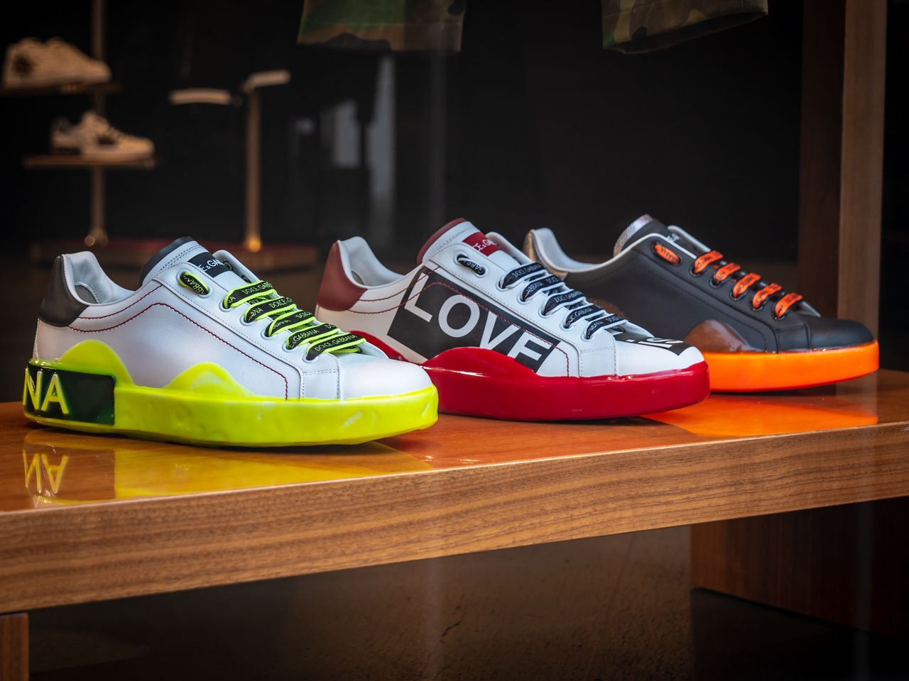 our-story Vibrant colored sneakers displayed on a wooden table in a London store.